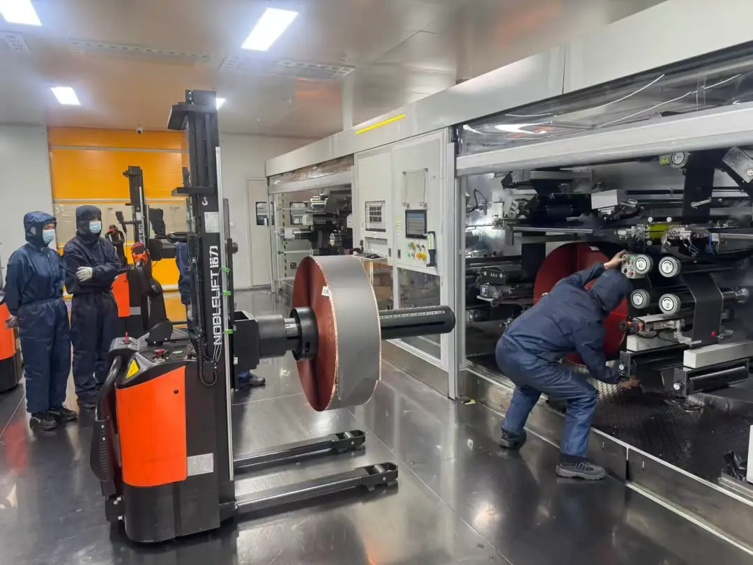 Forklift operator handling jumbo roll material in the New Energy Battery Cell workshop during a forklift skills competition