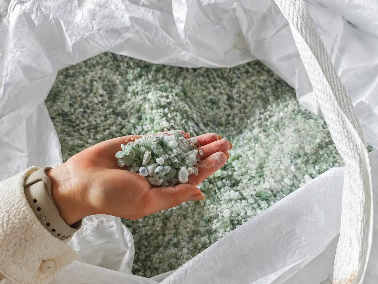 Granular fluorspar sample in hand showing particle size and bulk packaging